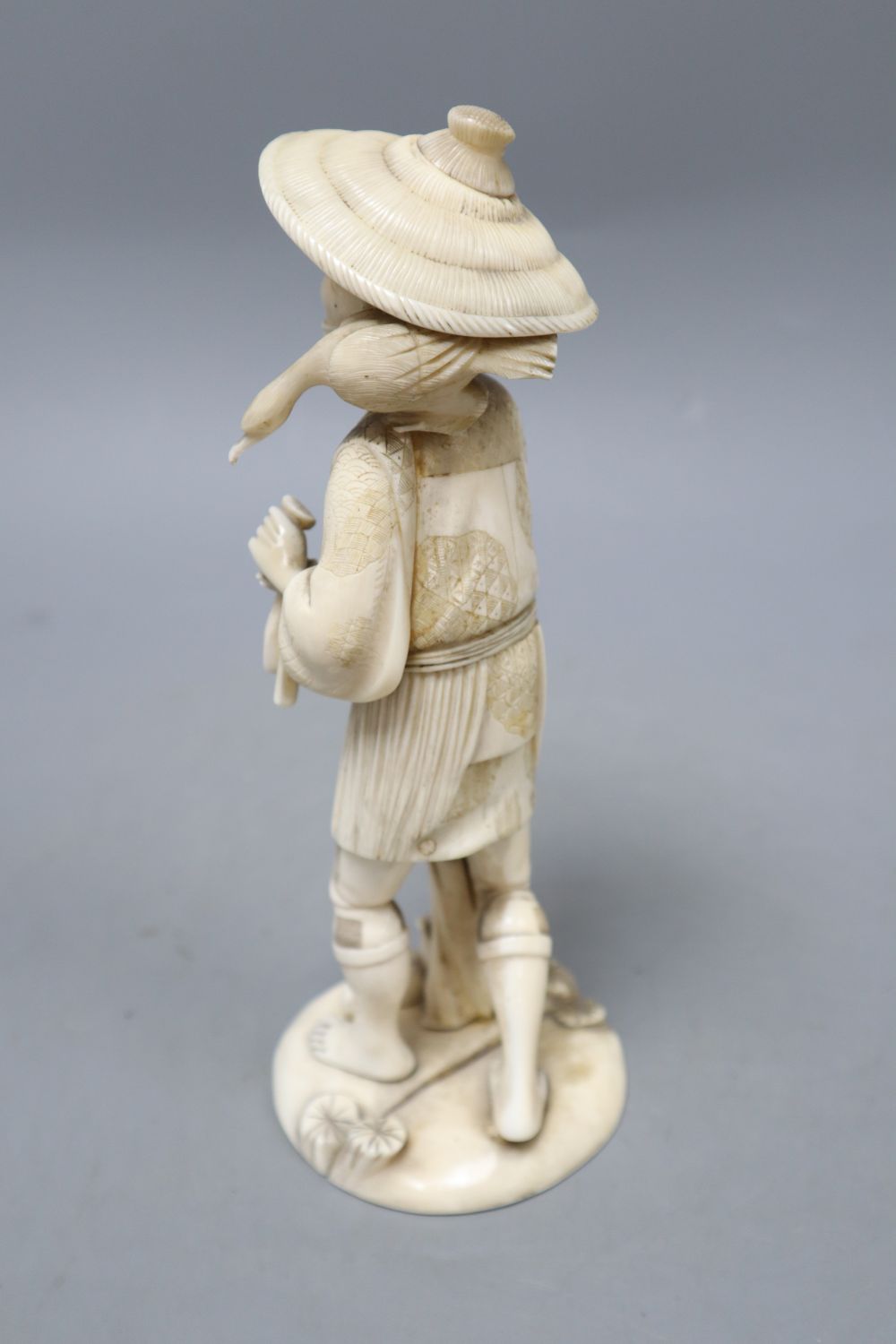 A Japanese sectional walrus ivory figure of a cormorant fisherman, character marks to base, height 23cm